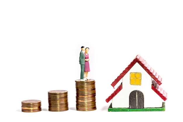 A person holding a miniature house and a stack of coins, representing asset management and its relation to financial aid.