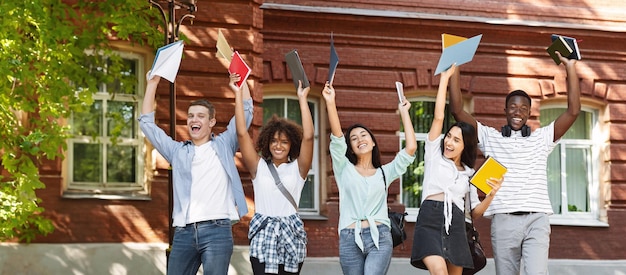 A diverse group of college students celebrating with diplomas in hand, with a backdrop of a university campus.