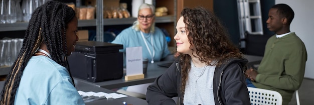 A student working at a university library, assisting other students with research and book checkout. The scene should be well-lit and show the student helping others, emphasizing the service aspect of work-study programs.