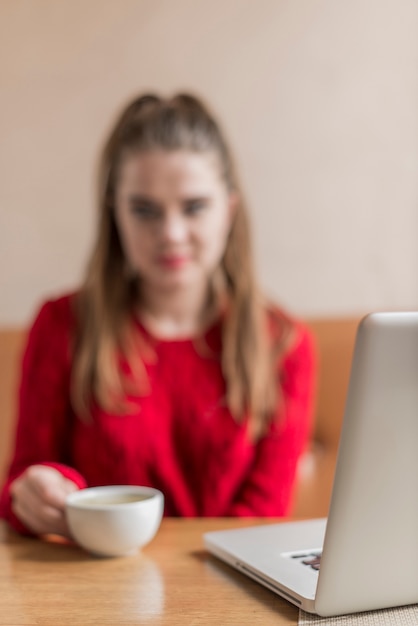 A student sitting at a desk, focused on filling out the FAFSA form on a laptop, with a calm and determined expression. Books and a cup of coffee are visible in the background.