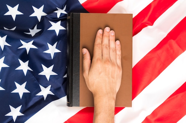 A close-up of a hand holding a graduation cap with a U.S. flag in the background, symbolizing educational achievement through military financial support.