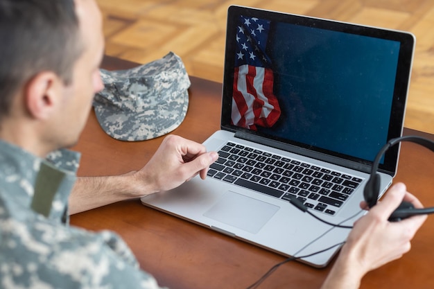 A veteran using a laptop with the VA website displayed, focusing on the GI Bill application process with a supportive family member beside him.