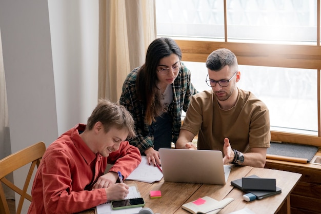 A family sitting at a table, reviewing financial documents together, such as tax returns and bank statements, with a laptop displaying a college cost calculator.