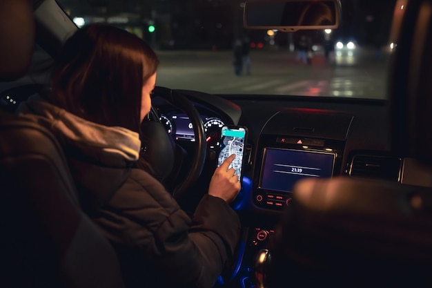 A sleek, futuristic-looking self-driving car navigating a city street at night. The car's headlights illuminate the road ahead, and AI-powered sensor displays are visible on the dashboard.