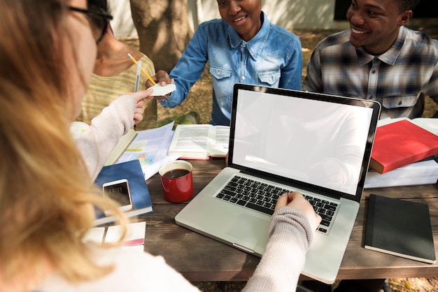 An open laptop displaying a student loan forgiveness application form, with a diverse group of students collaboratively working on it in the background.