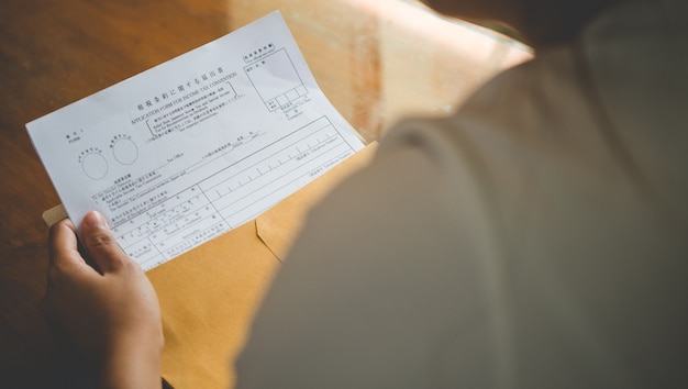 A close-up shot of a hand holding a US tax form with the EITC section highlighted. The background is blurred, focusing on the form and the pen poised to fill it out.