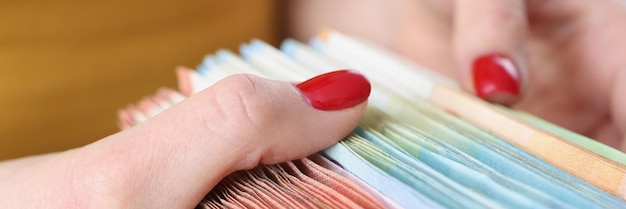 A close-up of a hand holding various receipts and documents related to adoption expenses. The receipts are neatly organized and include notes about their purpose.
