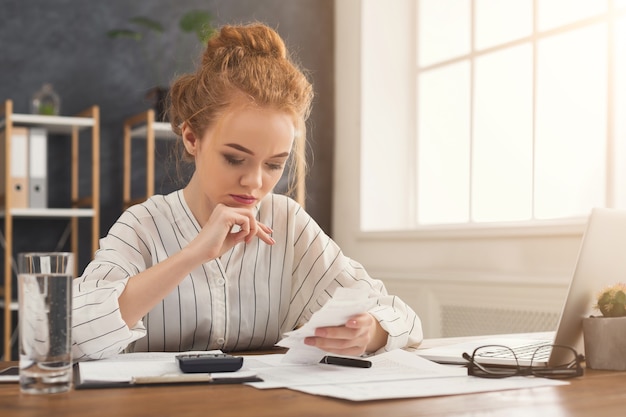 A person sitting at a desk, using a calculator and reviewing tax forms. The forms are related to the Adoption Tax Credit, and the person is carefully calculating the credit amount.