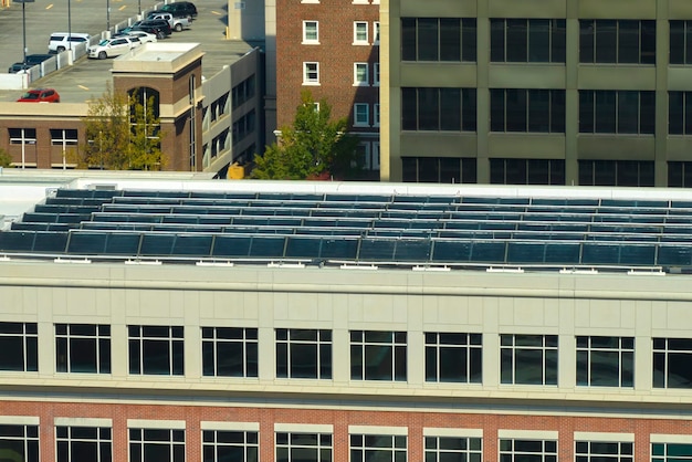 A close-up view of a solar panel array on a commercial building's roof. The panels are neatly arranged, reflecting sunlight. The background includes an urban skyline, suggesting the integration of renewable energy in business settings.