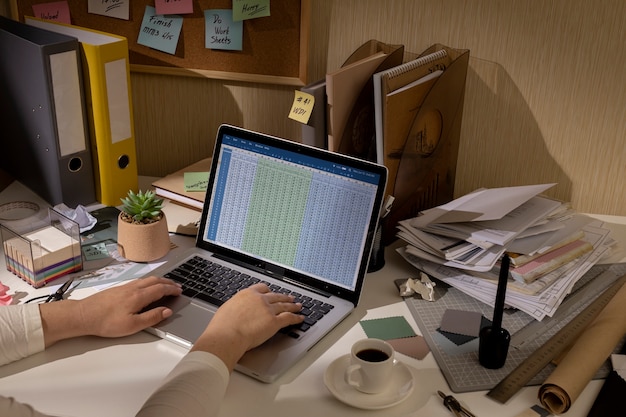 A person working on a laptop, surrounded by financial documents and spreadsheets, emphasizing the process of calculating the QBI deduction.
