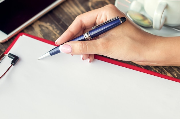 A close-up of a hand holding a pen, filling out a financial aid appeal form. The background is blurred with various financial documents. The image should convey attention to detail and the importance of accuracy.
