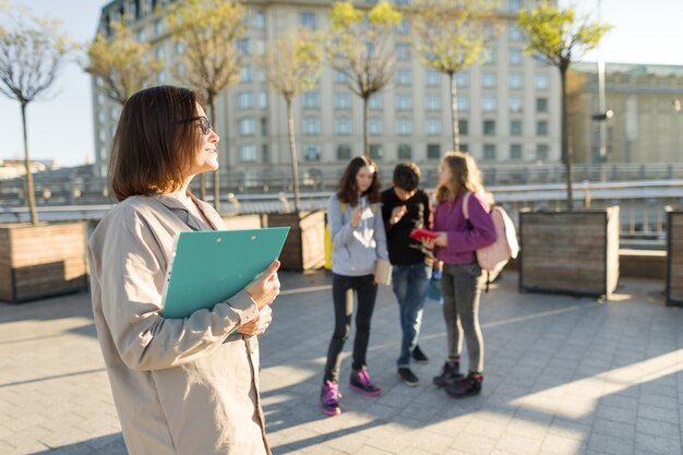 A student reviewing documents on a college campus, with a blurred background of other students and campus buildings. The image should suggest research and preparation.