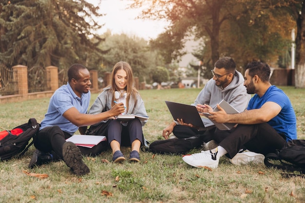 A diverse group of college students studying together on a campus lawn, with a university building in the background. The scene conveys a sense of community and the pursuit of higher education despite financial challenges.