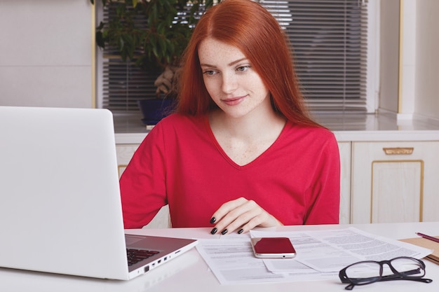 A close-up shot of a student filling out a financial aid application form on a laptop, with a calculator and various documents related to income and expenses spread around.