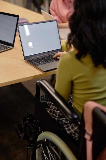 A close-up of a student's hands using assistive technology on a laptop in a classroom setting, highlighting the support available for students with disabilities.