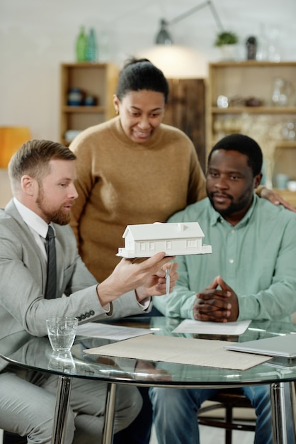 A diverse group of people sitting at a table with a housing counselor, reviewing documents and discussing affordable housing options. The scene emphasizes guidance and support.