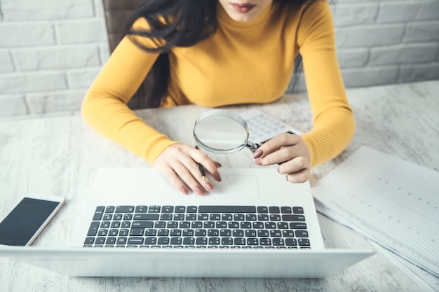 A person using a laptop to search for legal aid resources online, with a magnifying glass hovering over the screen. The atmosphere is supportive and resourceful.