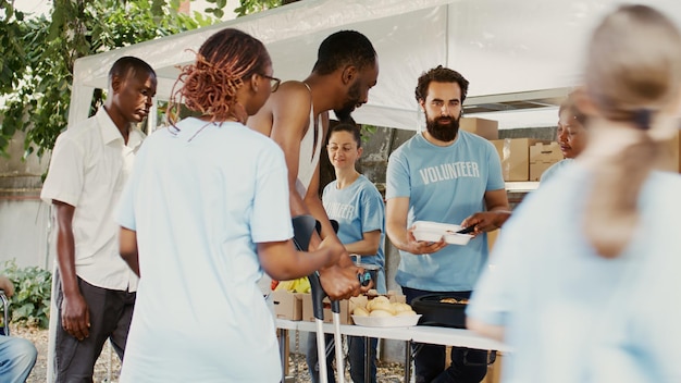A diverse group of people standing in line at a food bank, receiving assistance from volunteers. The scene is orderly and respectful, with a focus on providing essential support.