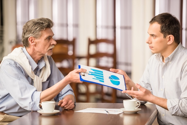 A split-screen image. On one side, a SCORE mentor is meeting with a small business owner in a coffee shop, discussing business strategies. On the other side, a group of entrepreneurs is attending a workshop at an SBDC, learning about digital marketing.