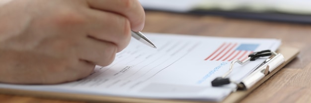 A close-up of a hand filling out an unemployment application form. The form has various fields related to employment history and personal information. The background is blurred to keep the focus on the form.