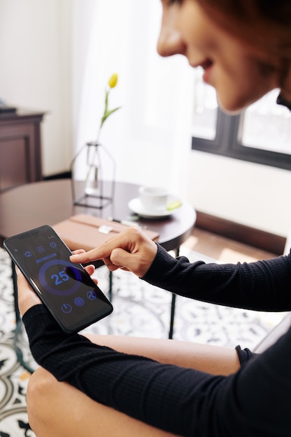 A close-up of a smart thermostat controlling energy usage in a modern home. The interface shows various energy-saving settings and real-time energy consumption data.