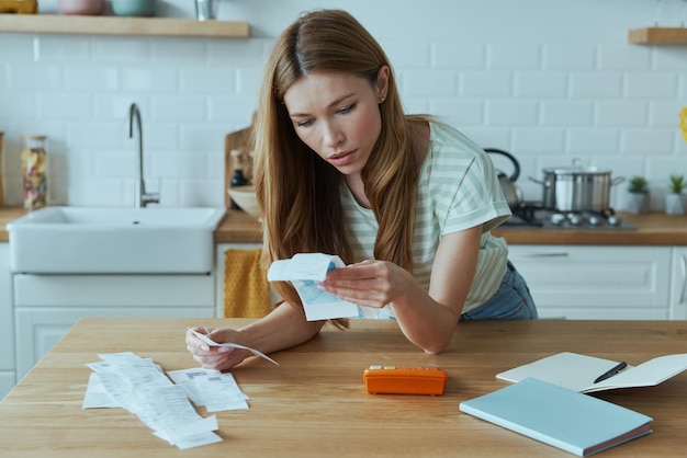 A person sitting at a desk, sorting through receipts and documents related to childcare expenses, with a calculator and tax form visible on the desk.