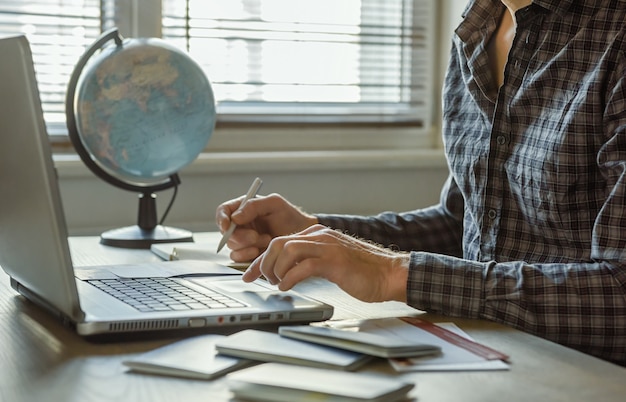 A person sitting at a desk, reviewing financial documents and using a calculator to optimize their foreign tax credit, with a globe and a laptop displaying tax software in the background.