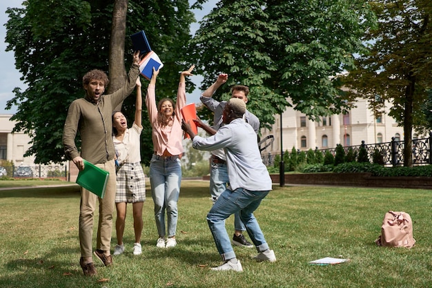 A diverse group of college students celebrating after receiving their Pell Grant awards, with smiles and thumbs-up gestures. The background shows a vibrant college campus with banners and flags.